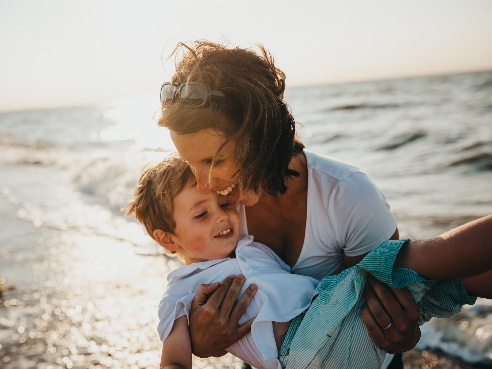 photo of mother and child beside body of water